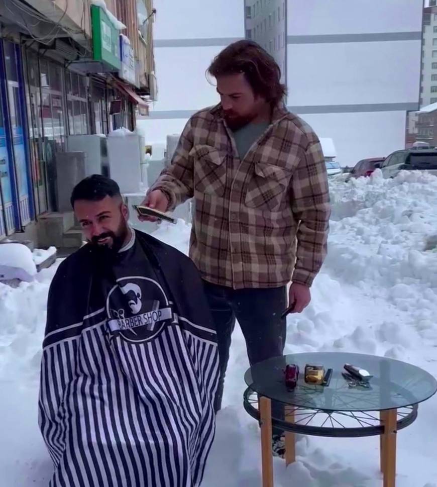 Berber, müşterilerini karda dükkanının önünde tıraş etti